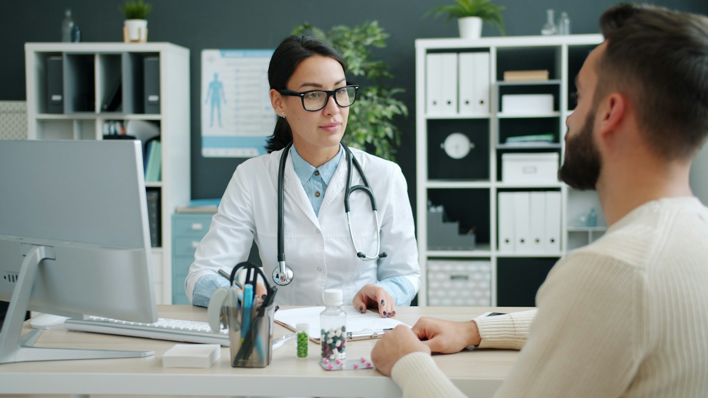 Fotografía referencial de una médica escuchando a un paciente durante una consulta